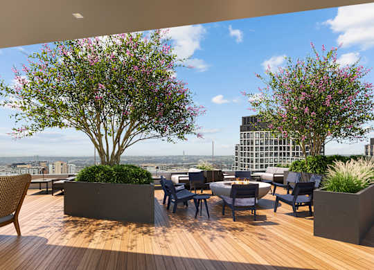 A wooden deck with a table and chairs and two flowering trees.