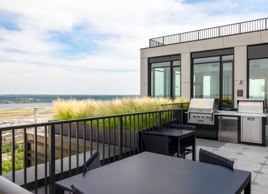 a patio with a grill and table on a balcony overlooking the beach at The Grace and Reva, Virginia, 22202