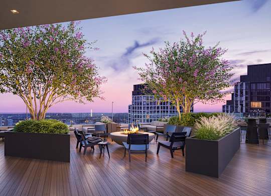 A wooden deck with a table and chairs and two trees.