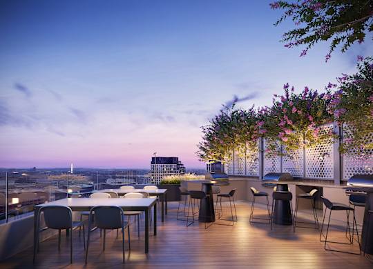 A balcony with a table and chairs overlooking a cityscape at dusk.