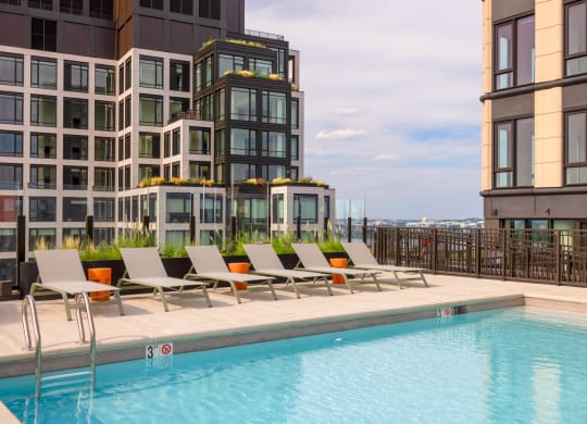 a swimming pool with lounge chairs next to a building at The Grace and Reva, Arlington, 22202