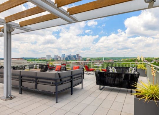 a rooftop patio with furniture and a city in the background