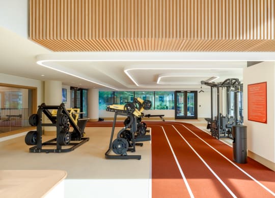 a gym with a row of exercise machines in the middle of a room at The Grace and Reva, Arlington, 22202