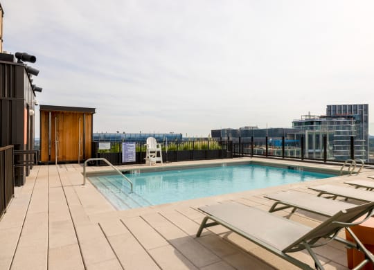 the pool on the rooftop of a building with chairs and a city in the background at The Grace and Reva, Arlington, Virginia