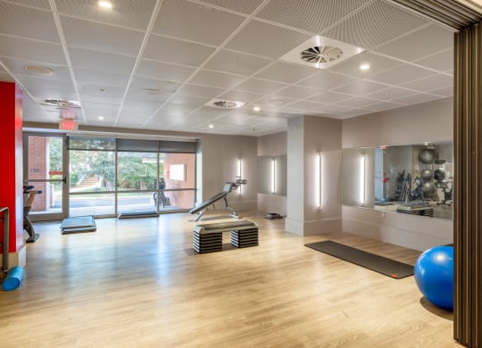 a gym with yoga mats and exercise equipment on a wooden floor