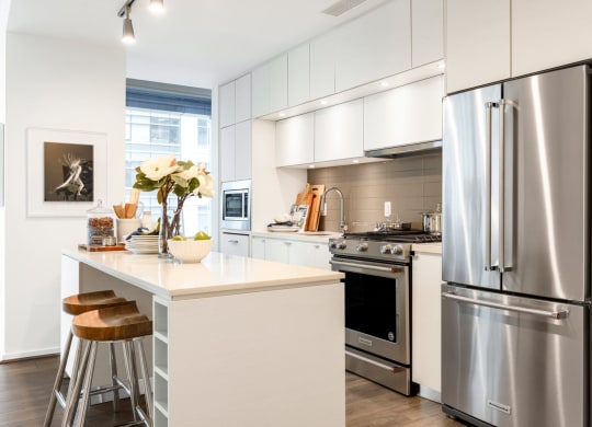 a white kitchen with stainless steel appliances and a counter top