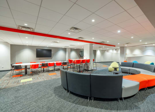 a lounge area with chairs and tables and a tv
