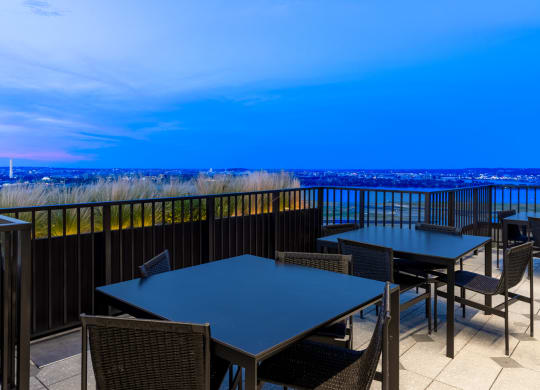 a terrace with tables and chairs overlooking the ocean and the city at night at The Grace and Reva, Arlington, Virginia