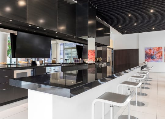 the kitchen has a bar with stools and a large tv