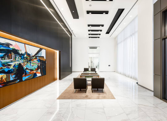 a large lobby with a table and chairs and a large painting on the wall