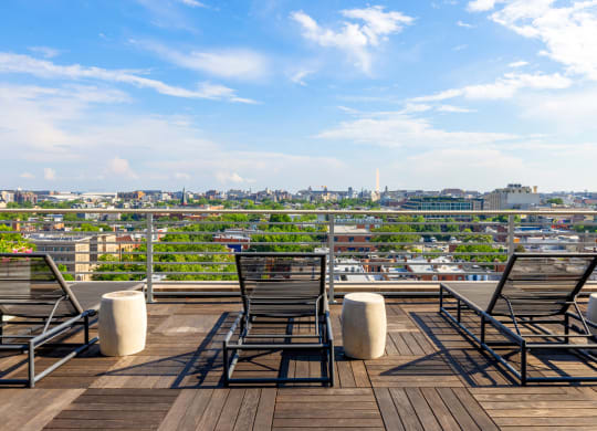a rooftop deck with chairs and a view of the city