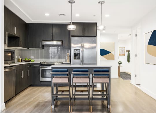 a kitchen with dark cabinets and a large island with a breakfast bar