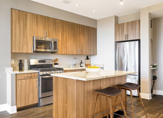 a kitchen with wooden cabinets and a counter with two stools  at The Bartlett, Arlington, VA, 22202
