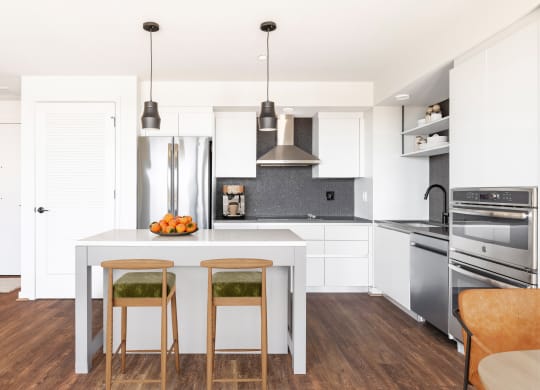 a kitchen with white cabinets and a white island with three stools