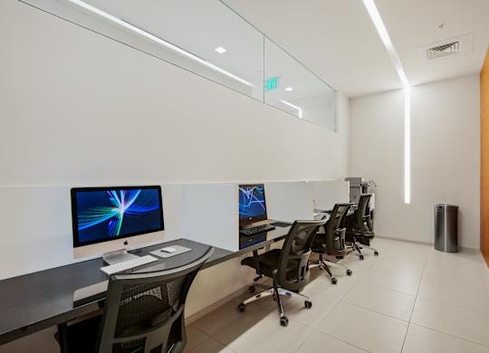 A modern office with a glass wall and a green exit sign.