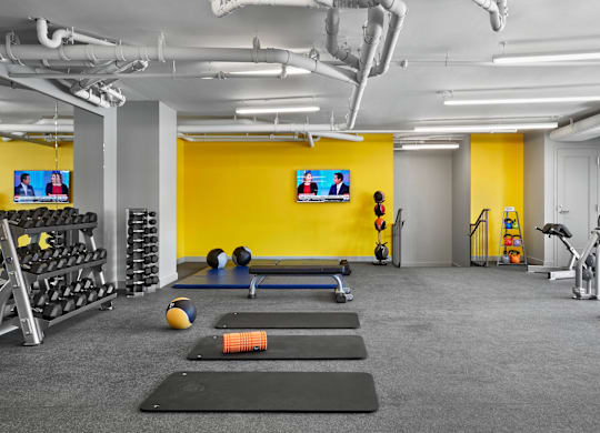 A gym with a variety of equipment including weights, a bench press, and a treadmill.
