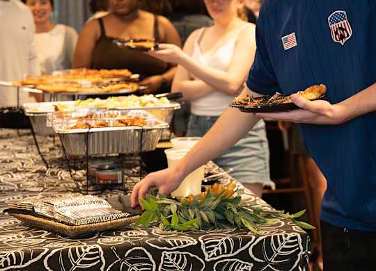 A man in a blue shirt with an American flag on it is serving food from a tray.