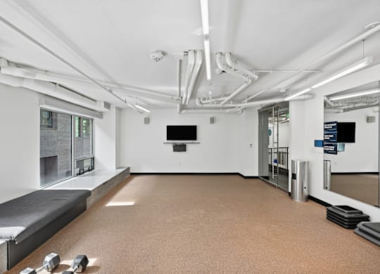 A spacious room with a bench, mirrors, and a television.