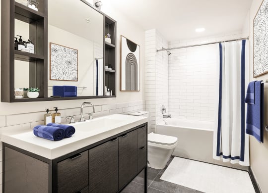 a bathroom with white tile walls and a white sink with a blue towel on it