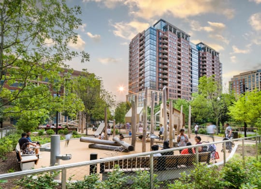 people walking around a playground in a park with tall buildings at The Grace and Reva, Arlington, Virginia