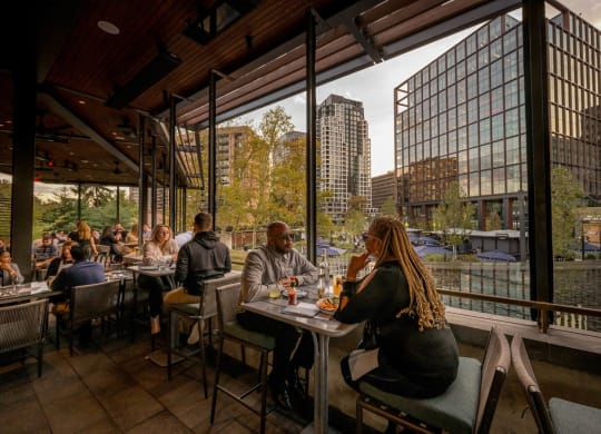 people sitting at tables in a restaurant overlooking a river at The Grace and Reva, Virginia, 22202