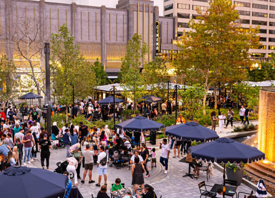 a crowd of people in a park with umbrellas at The Grace and Reva, Arlington, 22202