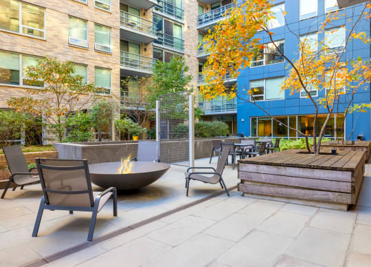 an outdoor patio with chairs and a fire pit in front of an apartment building