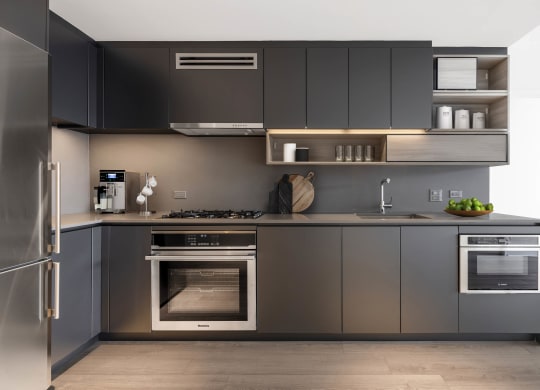 a kitchen with gray cabinets and stainless steel appliances