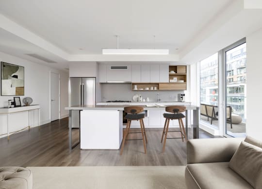 a kitchen with white cabinetry and a white island with three wooden stools