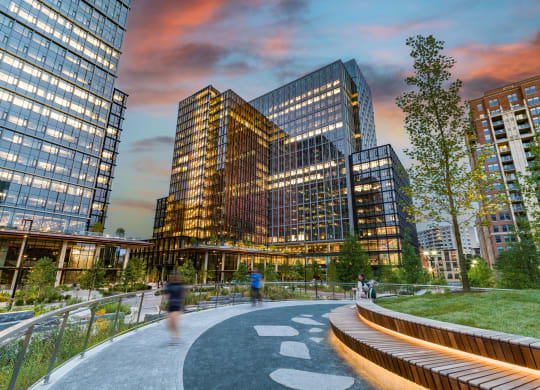 people walking around a park in front of tall buildings