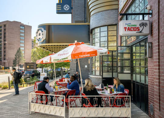 people sitting at tables outside of a restaurant in front of a building