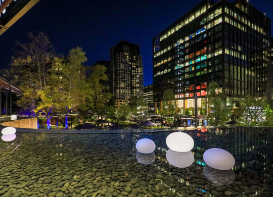 a pool of water at night with buildings in the background