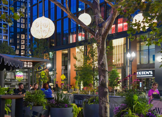 people sitting at tables outside of a restaurant at night