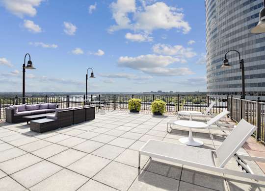 A patio with a couch, chairs, and a table with a view of the water.