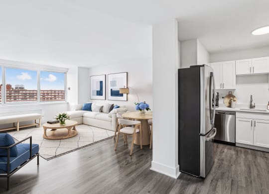 a living room with a white couch and a kitchen with stainless steel appliances