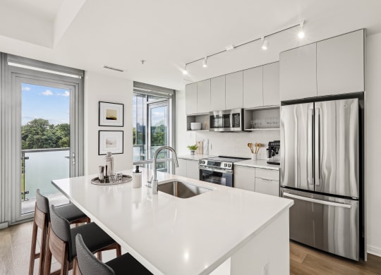 a white kitchen with a large island and stainless steel appliances