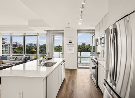 a white kitchen with a large island and stainless steel appliances