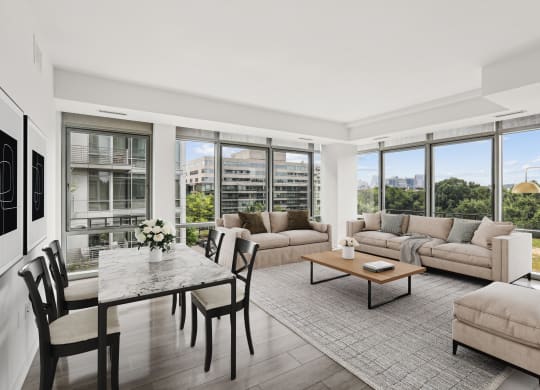 a living room with couches and a table with chairs and large windows