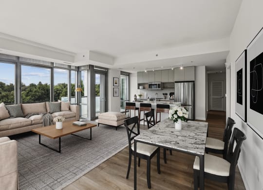 a living room with couches and a table and a kitchen with a large window