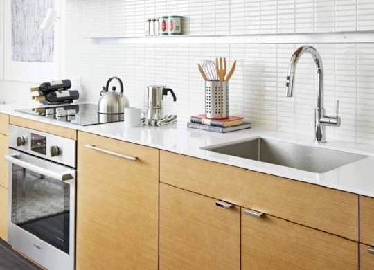 A kitchen with wooden cabinets and a white backsplash.