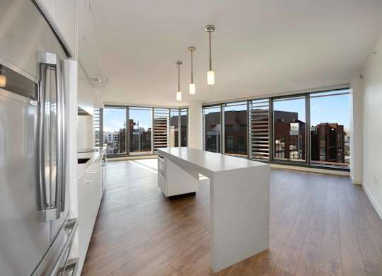 A modern kitchen with a refrigerator, wooden floors, and a large window.