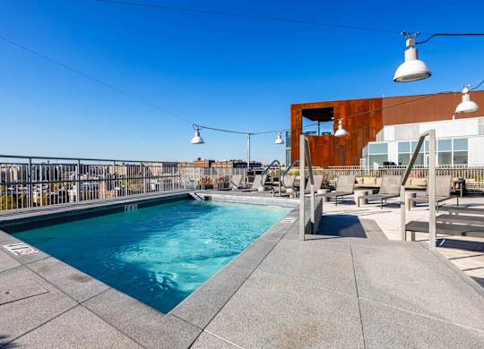 A swimming pool with a concrete edge and a building in the background.