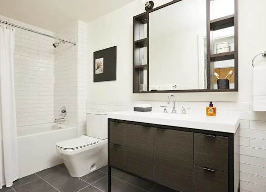 A white bathroom with a toilet, sink, and mirror.
