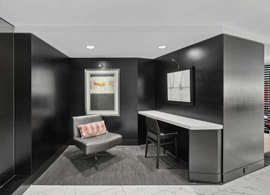 A black and white photo of a room with a couch, chair, and desk.