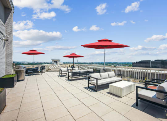 the rooftop terrace of a building with couches and umbrellas