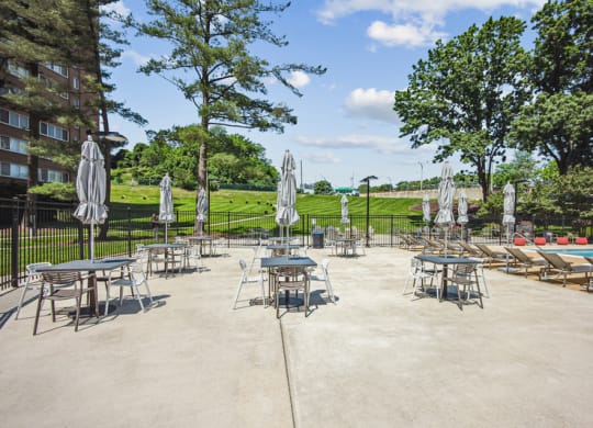 a patio with tables and umbrellas next to a pool