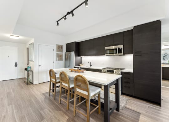a kitchen with a white island and wooden chairs at The Grace and Reva, Virginia, 22202