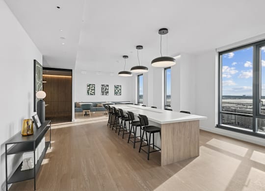 A modern kitchen with a long bar and a view of the city.