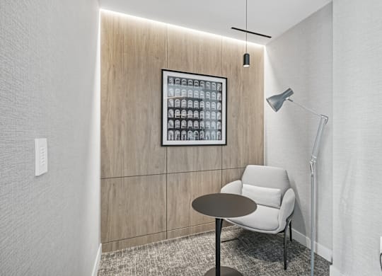 A modern room with a table, chair and a lightbox on the wall.