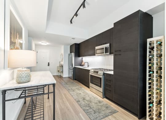 a kitchen with dark wood cabinets and white countertops and a table with a lamp at The Grace and Reva, Virginia